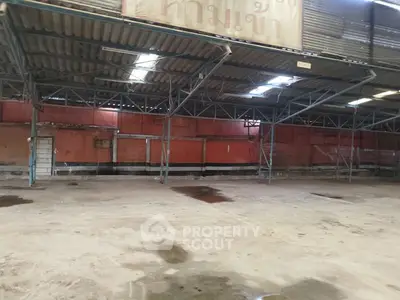 Spacious industrial warehouse with high ceilings and metal framework, ideal for storage or manufacturing.