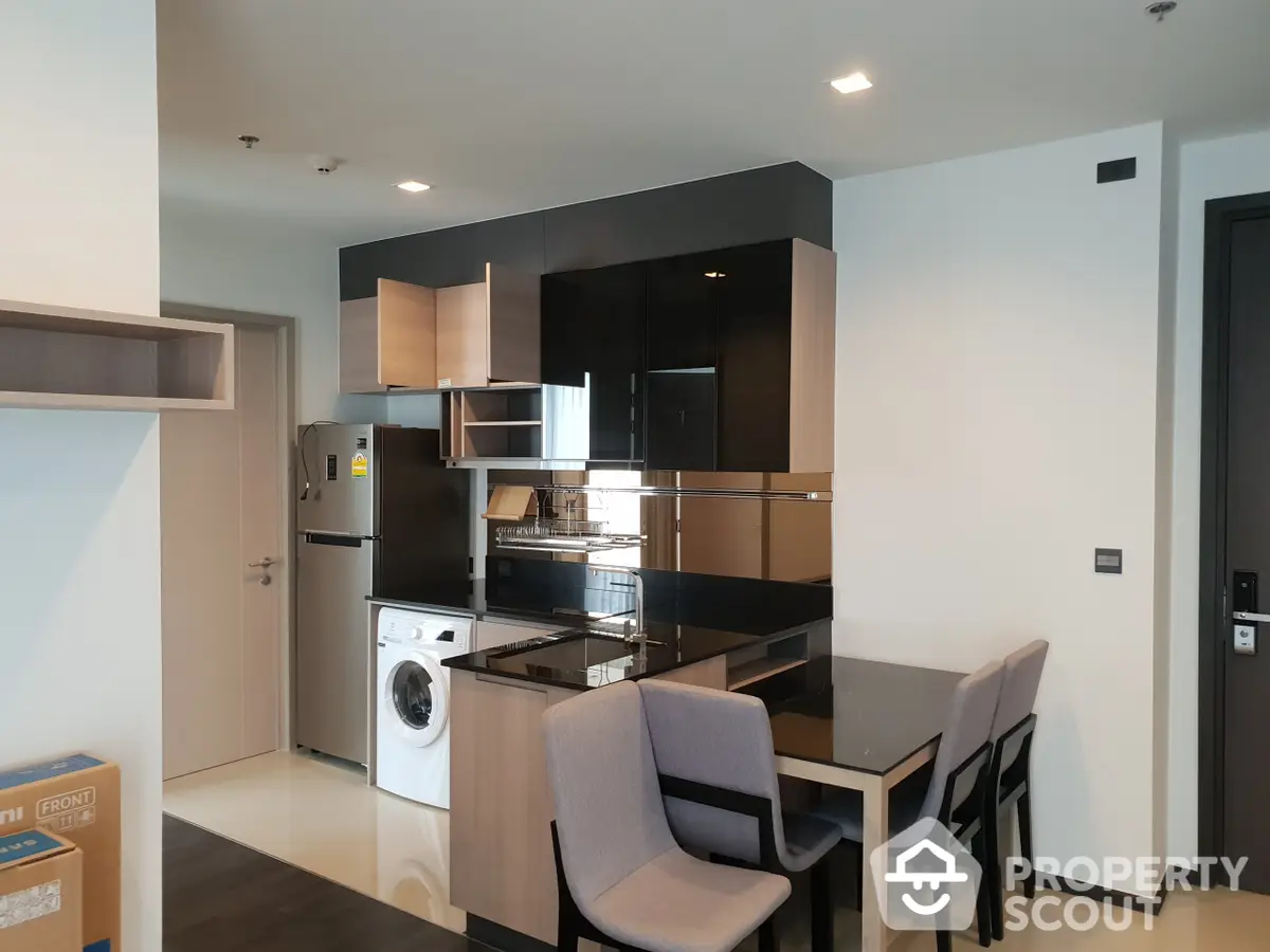 Modern kitchen with sleek black appliances, including a gas stove and oven, complemented by wooden cabinetry and a cozy dining area.