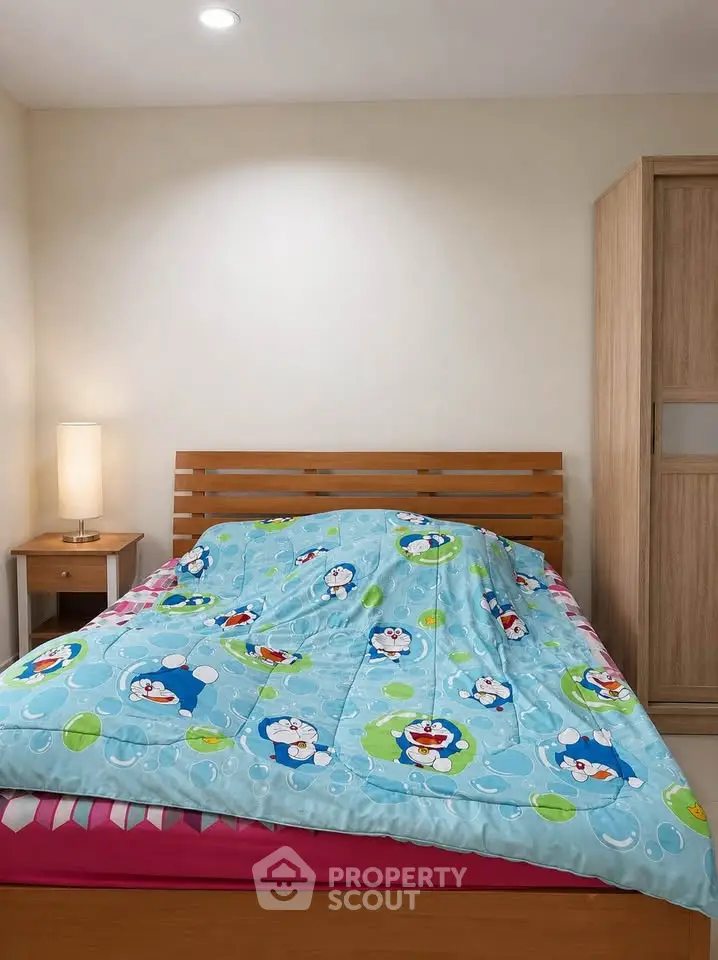 Cozy bedroom with wooden bed frame and playful themed bedding, perfect for a child's room.