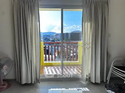 Bright living room with sliding glass doors leading to a sunny balcony with mountain views.