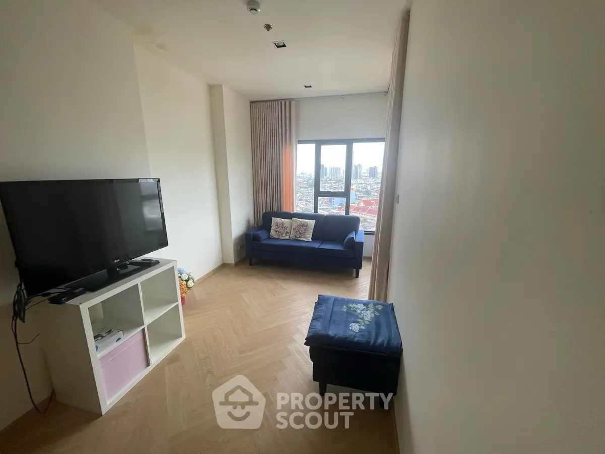 Modern living room with city view, featuring a cozy sofa and flat-screen TV, perfect for relaxation.