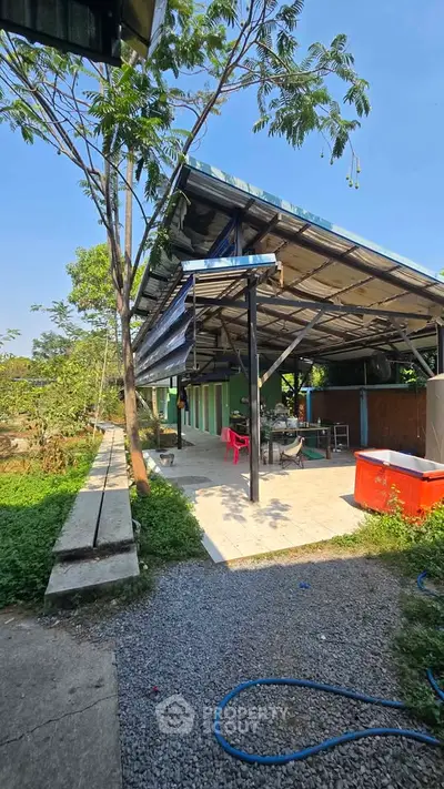 Spacious outdoor area with modern roofing and lush greenery, perfect for gatherings.