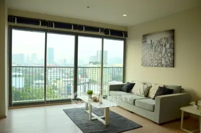 Spacious living room with city view and modern decor in high-rise apartment.