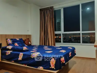 Cozy bedroom with city view, featuring a comfortable bed and large window for natural light.