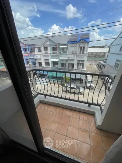 Charming balcony view overlooking residential street with modern houses and clear blue sky.