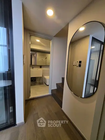 Modern apartment hallway with sleek mirror and view into stylish bathroom