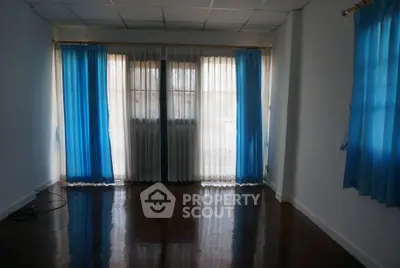 Spacious empty room with blue curtains and polished wooden floor