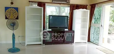 Spacious living room with TV, shelves, and garden view through sliding doors.