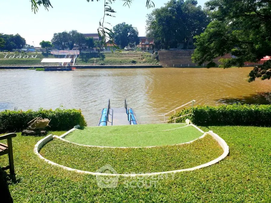 Riverside garden with lush greenery and serene water view, perfect for relaxation and leisure.