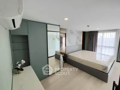 Modern bedroom with sleek design, large window, and built-in wardrobe in a stylish apartment.