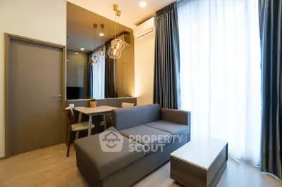 Modern living room with stylish sofa and dining area, featuring elegant lighting and large windows.