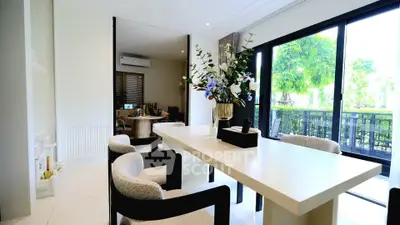 Elegant dining area with modern decor and large windows overlooking lush greenery.