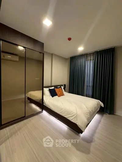 Modern bedroom with sleek design, featuring a cozy bed and mirrored wardrobe.