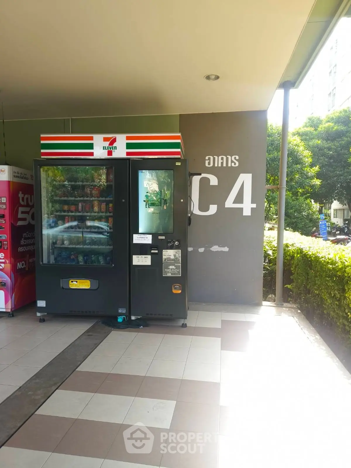 Modern building entrance with vending machine and lush greenery