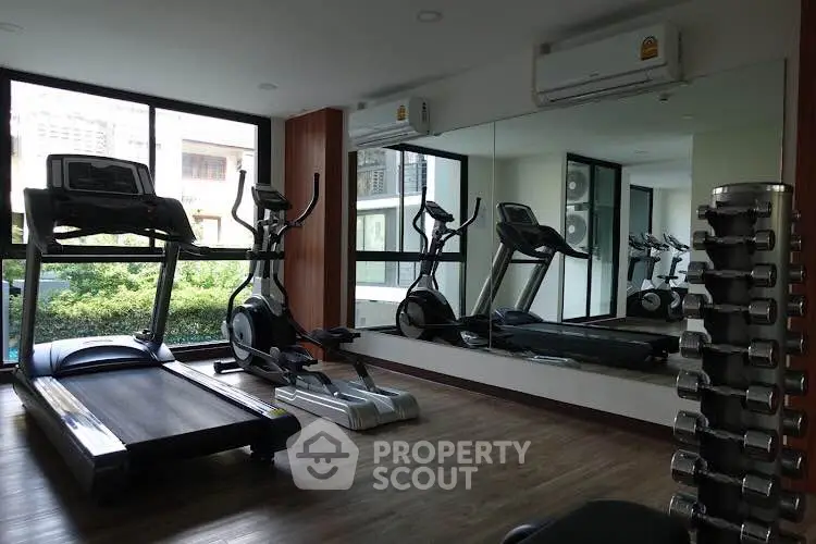 Modern gym with treadmill and exercise equipment in a bright, mirrored room.