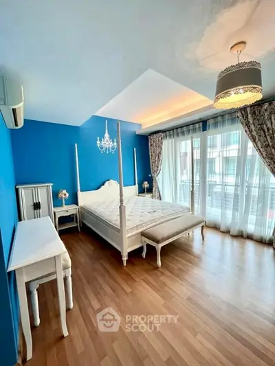 Elegant bedroom with blue accent wall and large windows for natural light.