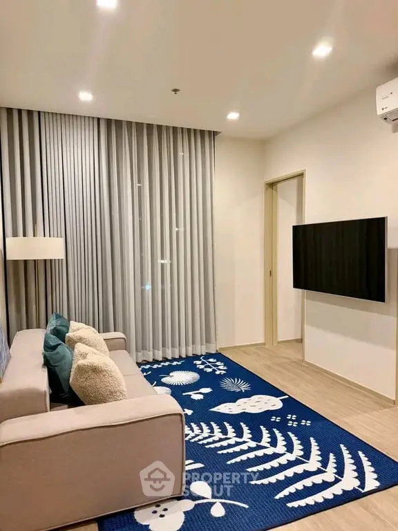 Modern living room with stylish decor and wall-mounted TV, featuring a cozy sofa and elegant curtains.