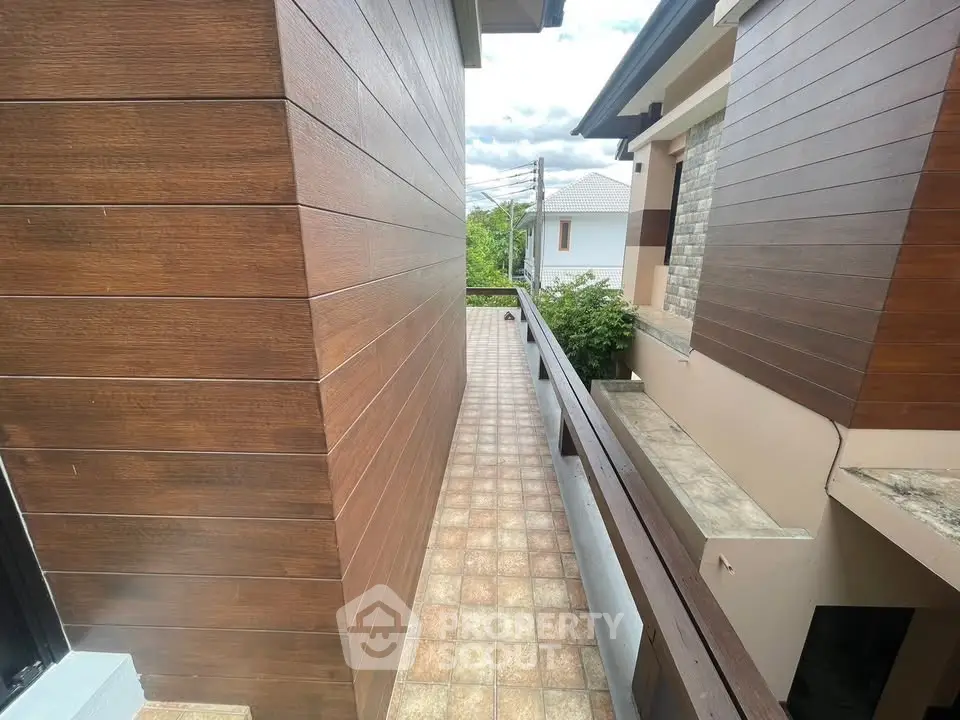 Charming narrow exterior walkway with modern wood paneling and scenic view.