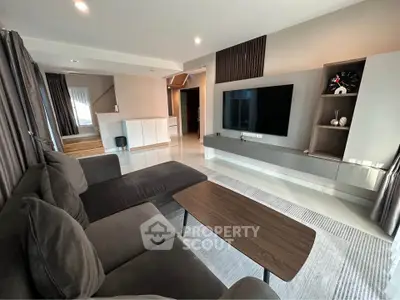 Modern living room with sleek design, featuring a large sectional sofa, wall-mounted TV, and stylish decor.