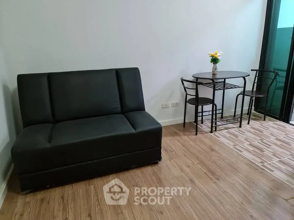 Cozy living room with modern black sofa and elegant dining set near balcony