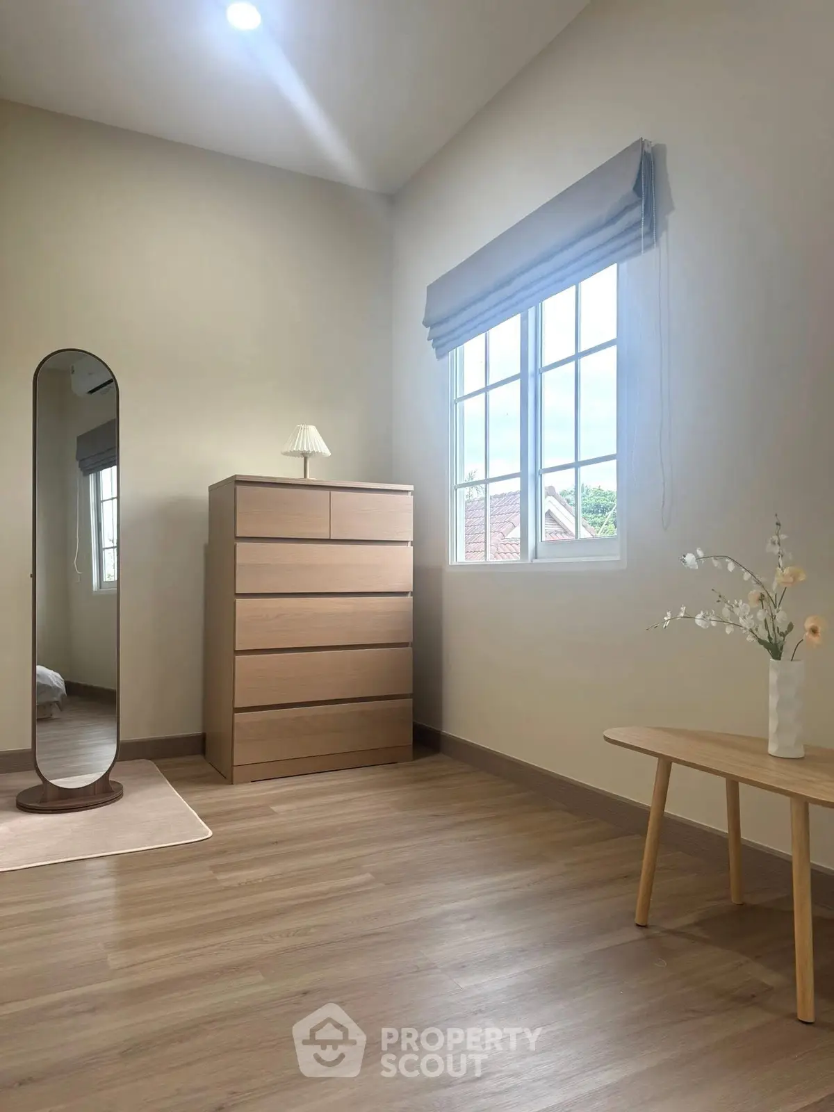Bright bedroom with modern wooden furniture and large window view.