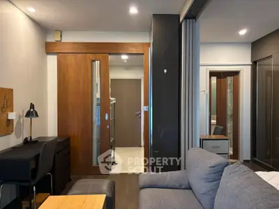Modern living room with sliding wooden door and cozy gray sofa in stylish apartment.