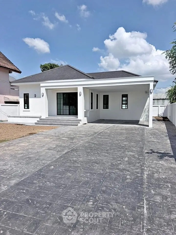 Modern single-story house with spacious driveway and sleek design under a clear blue sky.