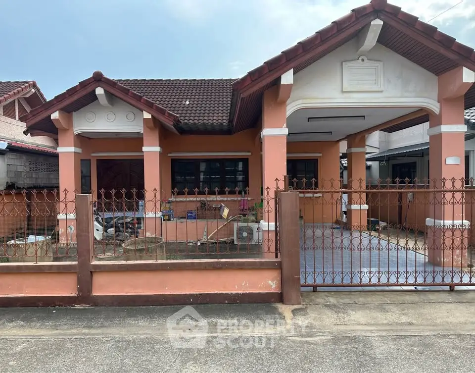 Charming single-story house with red-tiled roof and fenced front yard in a quiet neighborhood.