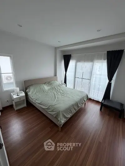 Spacious bedroom with large windows and wooden flooring, offering ample natural light and modern design.