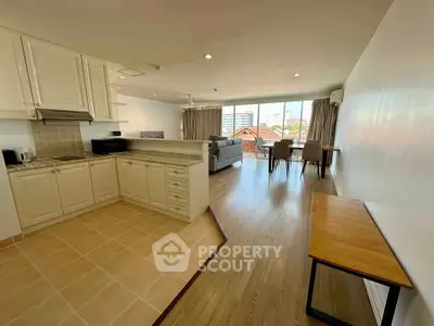 Spacious open-plan living room with kitchen and dining area, featuring large windows and modern furnishings.