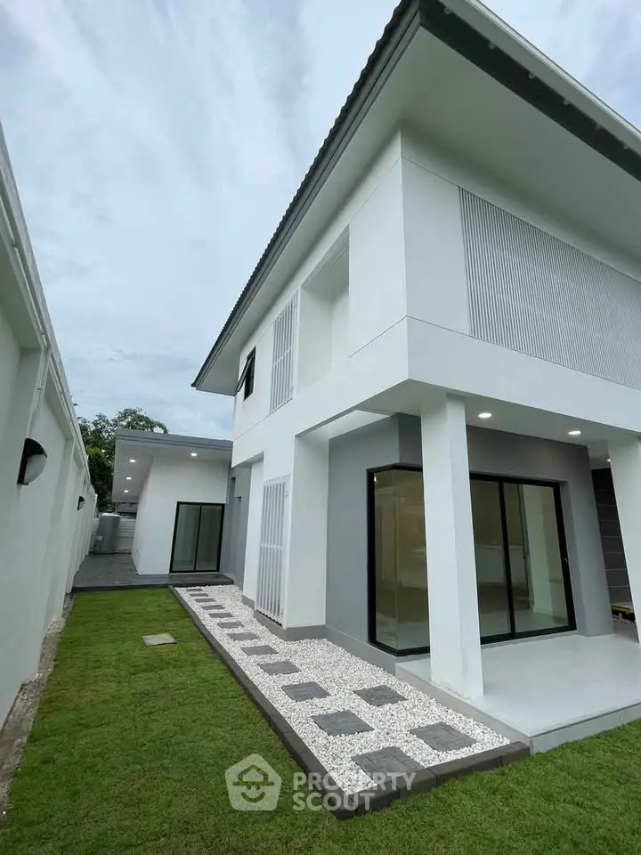 Modern two-story house with sleek design and manicured lawn, showcasing contemporary architecture.