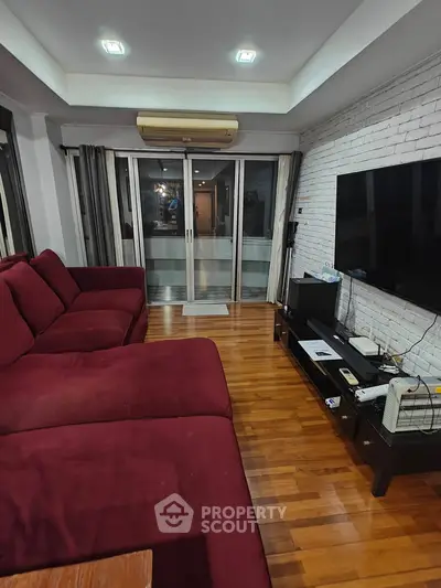 Spacious living room with red sofa and large TV, featuring wooden flooring and modern decor.