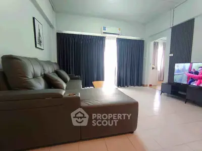 Spacious living room with modern leather sofa and large TV, perfect for relaxation.
