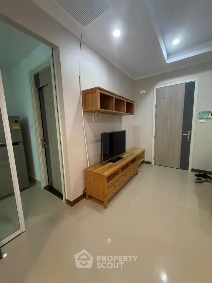 Modern living room with sleek wooden furniture and wall-mounted TV in a stylish apartment.