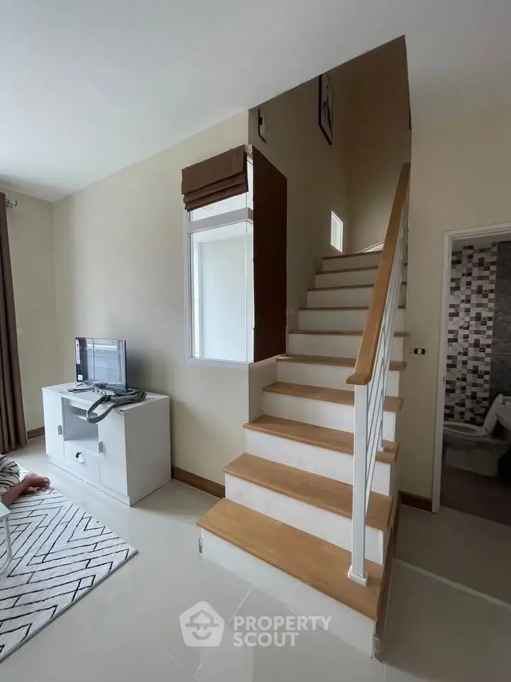 Modern interior with staircase and cozy living area, featuring sleek design and neutral tones.