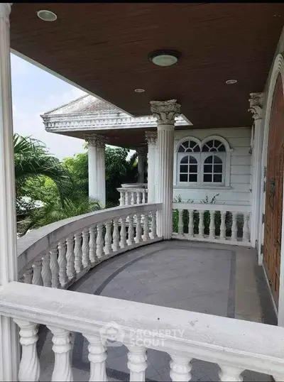Elegant balcony with classic columns and lush greenery view