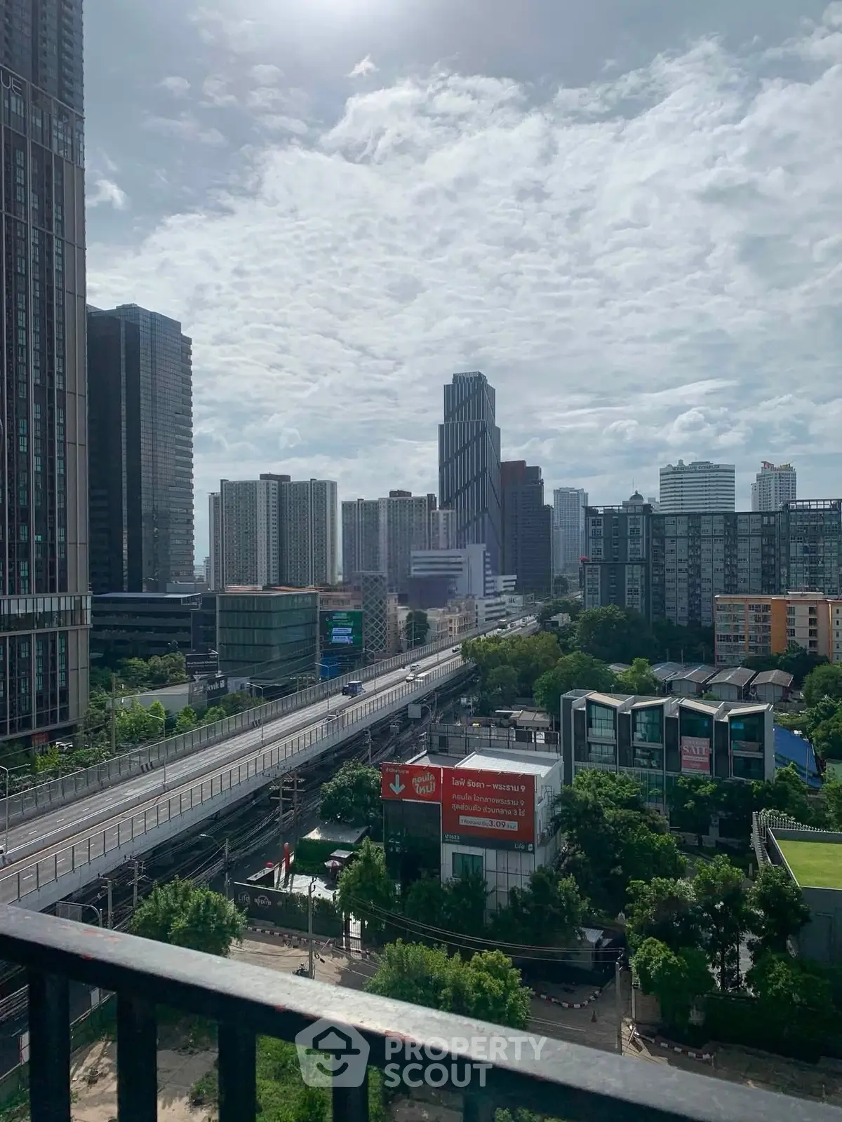 Stunning cityscape view from a high-rise balcony overlooking urban skyline and lush greenery.