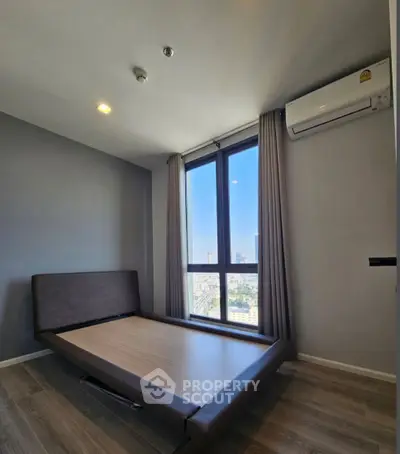 Modern bedroom with large window and city view, featuring sleek flooring and air conditioning.