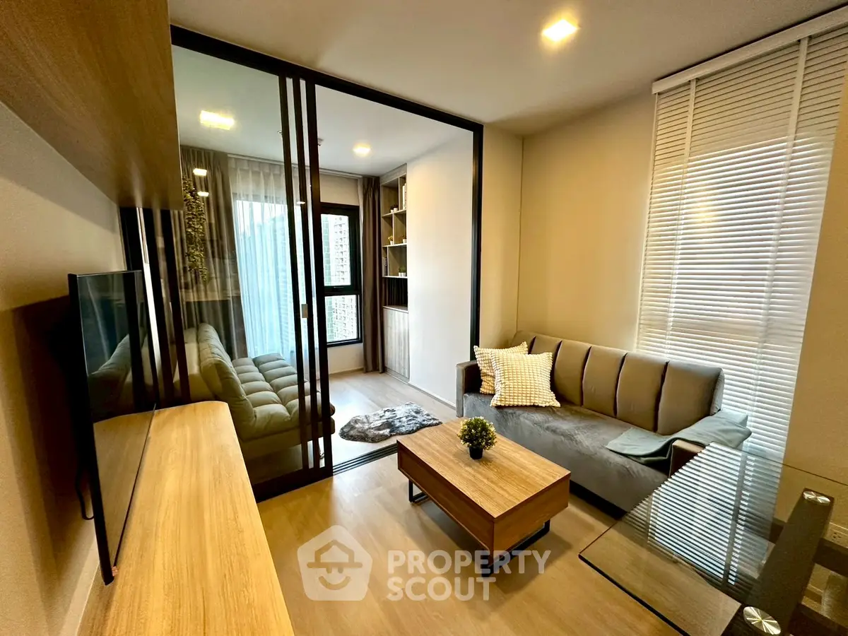 Modern living room with sleek furniture and glass partition in a stylish apartment.