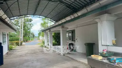 Spacious outdoor area with covered driveway and utility space in suburban home.