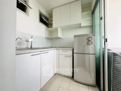 Modern compact kitchen with sleek white cabinets and stainless steel fridge