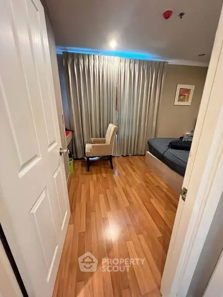 Cozy bedroom with wooden flooring and elegant curtains