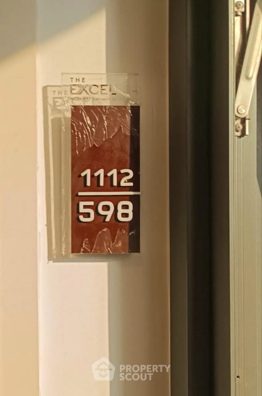 Modern apartment door number sign with sunlight reflection