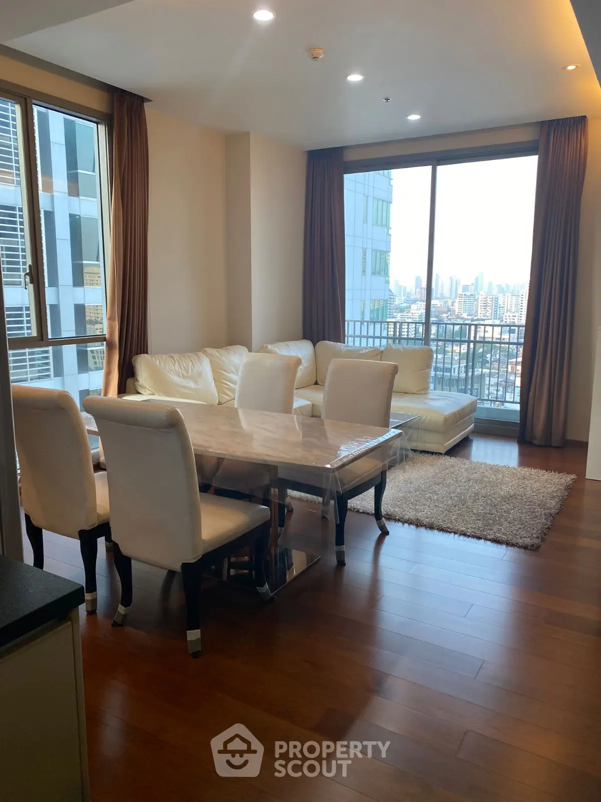 Spacious living room with city view, elegant furniture, and large windows.