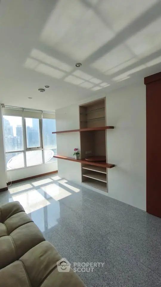 Spacious living room with large windows and built-in shelves in a modern apartment.