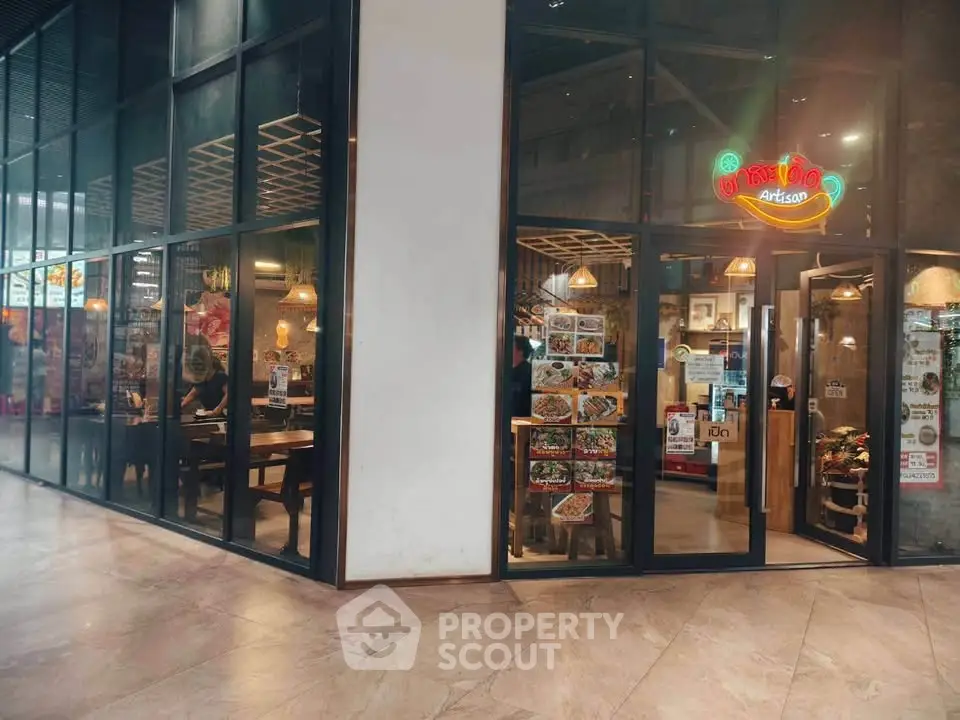 Modern restaurant exterior with glass walls in a shopping mall setting.