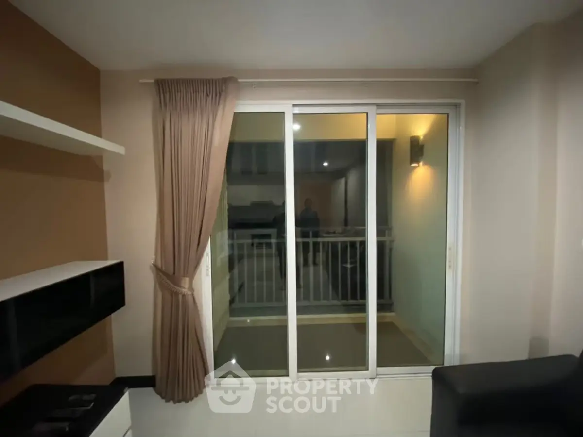Modern living room with sliding glass doors leading to a balcony, featuring elegant curtains and ambient lighting.