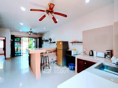 Spacious kitchen with modern appliances and open layout, featuring ceiling fans and a view of the pool area.