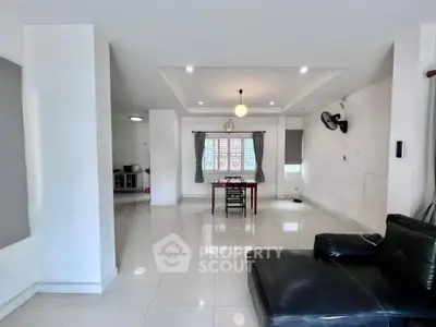 Spacious modern living room with sleek black leather sofa and dining area