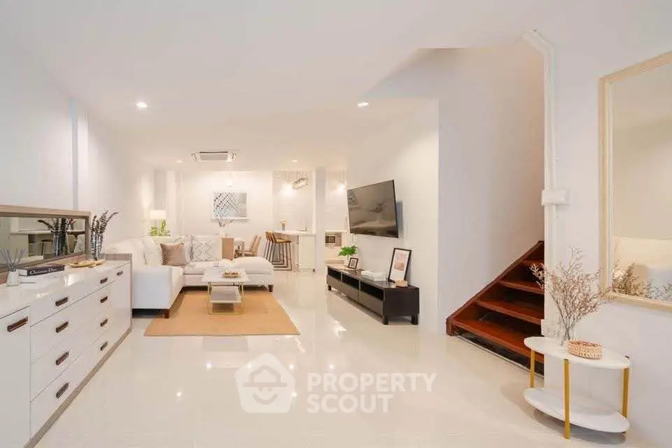 Spacious modern living room with elegant decor and staircase, perfect for family gatherings.